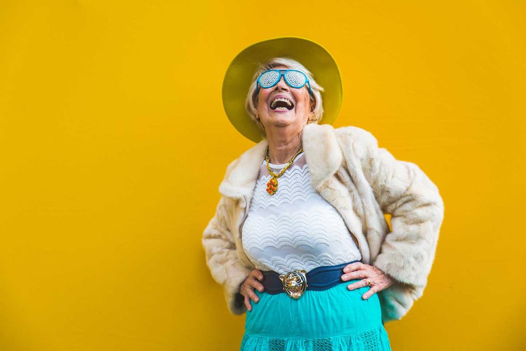 Laughing elderly woman whilst wearing 60s-fashion clothes