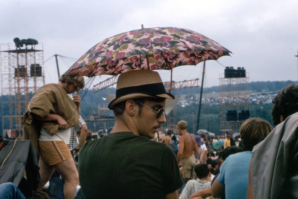 Man holding an umbrella to cover himself from the sun at the Woodstock Festival (1969)