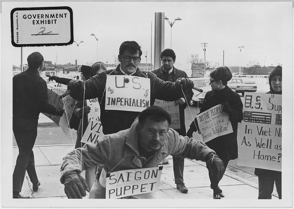 Protesters carry signs and act out "Saigon Puppet" demonstration in front of Wichita City Building (1967)