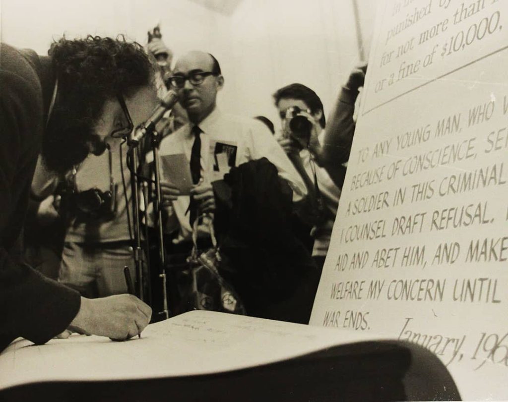Allen Ginsberg signing a petition at the "Draft Resistance Rally", United States (1968)