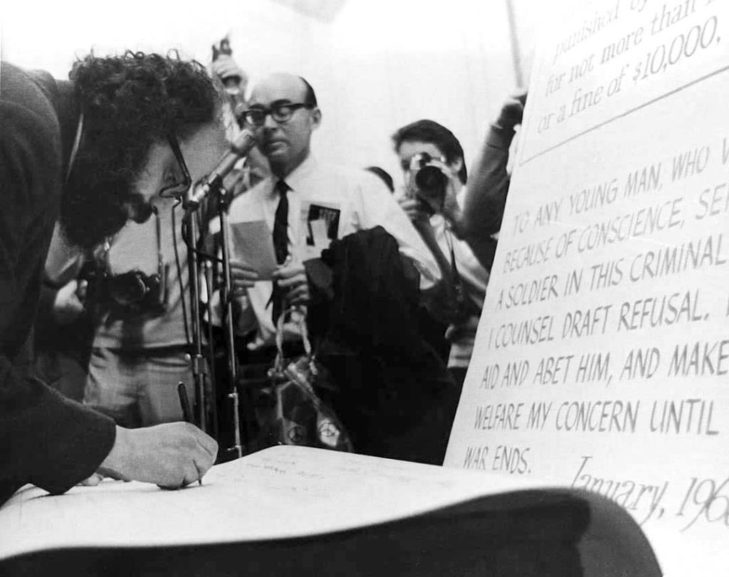 Allen Ginsberg signing a petition at the 'Draft Resistance Rally', United States (1968)