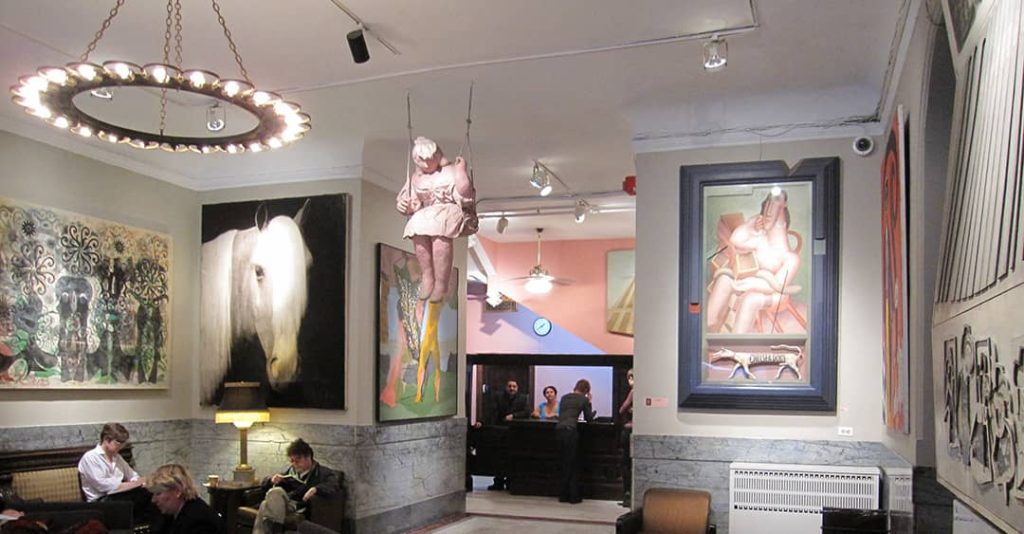 Lobby of the Chelsea Hotel with numerous paintings and a sculpture hanging from the ceiling (2009)