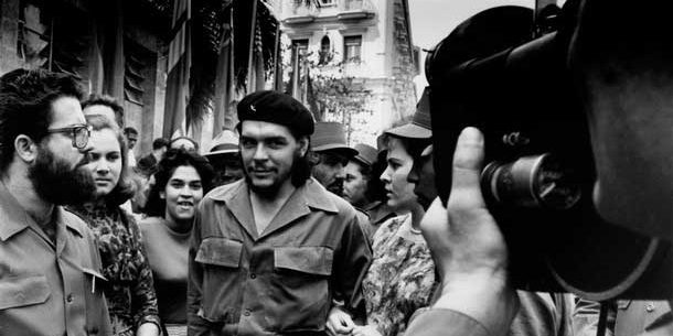 Che Guevara walking through a throng of cameramen down the streets in Havana