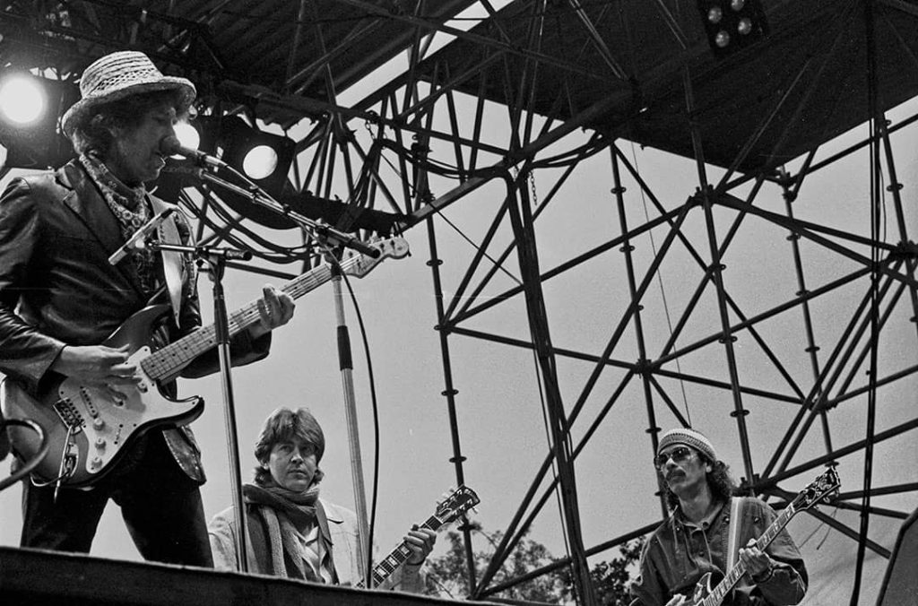 Bob Dylan (left) performing with Joan Baez (not pictured), Ex-Rolling Stone Mick Taylor (centre), and Carlos Santana (right) in Hamburg, Germany (1984)