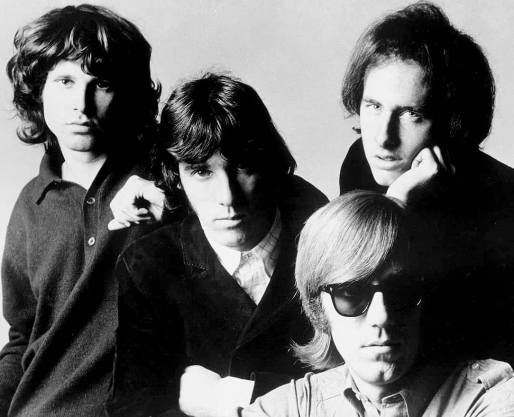Group photo of The Doors, from a promotional photo session in New York, USA. From left to right: Jim Morrison, John Densmore, Robby Krieger and seated, Ray Manzarek (1966)