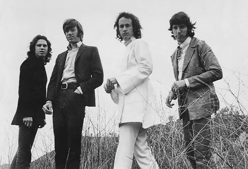 Photograph of The Doors members on a field. From left to right: Jim Morrison, Ray Manzarek, Robby Krieger ,and John Densmore (1969)